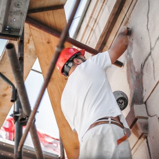Man worker standing on scaffolding, perform work on the restoration of the facade of the old building. Repairing and renovate